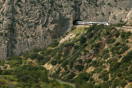 风景旅游火车在阿勒达斯大山谷中穿越一条隧道由山环绕的安纳卢西亚乘客图片