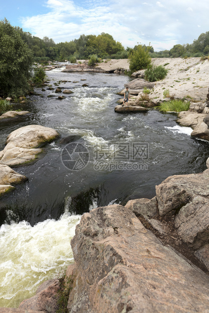 夏季一少年站在河岸块石头的边缘夏季一九年八十月七二河水流和YuzhnyBug河快速水流的景象天树荒野图片