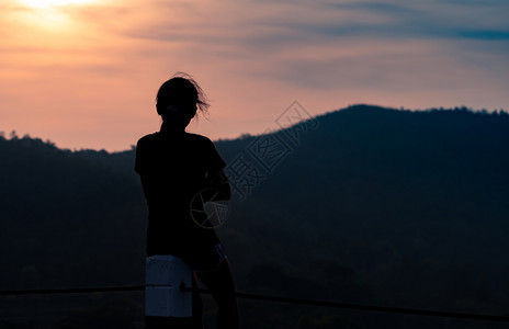 头脑一个女人坐在栅栏柱上看着山日出在早冒险旅行中女人独自旅行带着和平的心灵自然人静地坐着思考过去情绪化的冥想图片