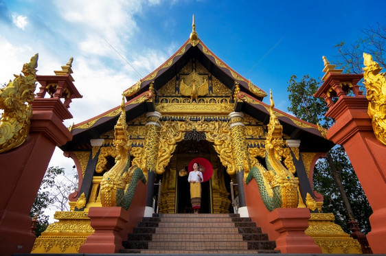 泰国南邦府湄他多伊帕占寺身穿泰北服饰的妇女打着红伞是旅游和朝拜佛塔多伊帕占寺的公共场所景观文化亚洲人图片