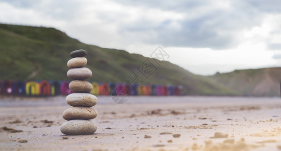 海边有模糊多彩的海滩背景在沙上堆积了十六块石头海滩上的质金字塔象征着稳定和谐平衡与浅深的田地冷静抽象丰富多彩图片