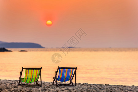 蓝色的水日出在沙热带滩和海浪两座甲板椅上美日初落夏在泰国尚塔胡里岛的礼帽卡休海滩上度过图片