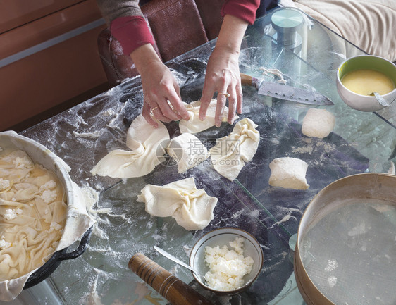 一种面包店揉女人双手在玻璃桌上卷着面团做蛋糕干芝士面包馅饼加卷心菜图片