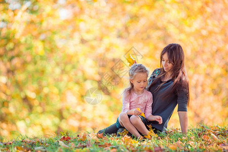 孩子乐趣手年轻妈和可爱小女孩在阳光明日的秋天公园有可爱小女孩在秋天的公园家庭在清晨享受温暖的天气小女儿和妈在秋天公园户外图片