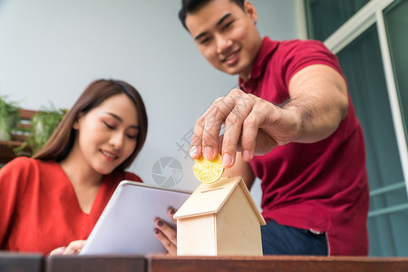 女士在室内家金币的选择焦点快乐的亚洲夫妇微笑因为它可以从投资中获利并且有购买房屋和住宿的储蓄投资概念和财务规划图片