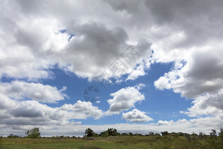 清楚的颜色条在草原上云层通过吞食最后一片蓝天而逐渐聚集蓝色的天空通过夏季草原上的稠密云层而浮现出来青色的天空在夏草原上图片