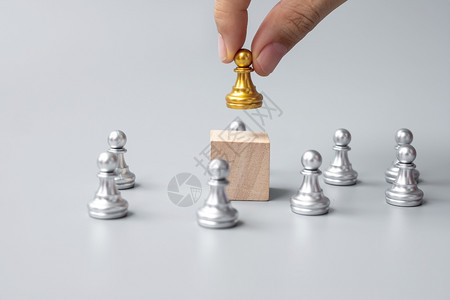工作人群公司的手握金象棋子的顶端或领头商人胜利领导才能商业成功团队招募和精神概念图片