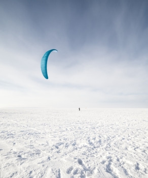 阳光速度Kite冲浪手被他的风筝拉扯穿过雪中滑板车在上放蓝风筝活动图片