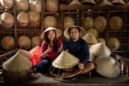 种族胡志明抽烟在越南霍希明市ApThoiPhuoc村的旧传统房屋中亚洲夫妇旅行者手工艺匠在传统术家概念中制作传统维特南帽图片