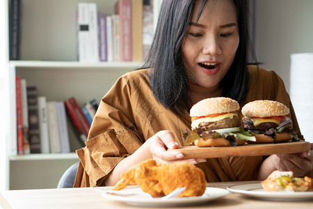 女士加大尺码饥饿的餐桌上炸鸡和披萨在家工作期间体重增问题百食不振BED概念BED家庭饮食紊乱症的概念背景图片