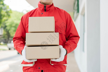 服务邮递员站立持有三箱包裹并等待分发给客户的邮递员分包交付概念以及等待向客户分发这些包裹员工新冠图片