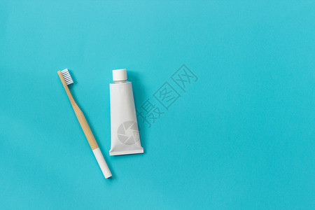 蓝色的天然环保竹刷白色毛和牙膏管套装用于在纸蓝色背景上洗涤复制文本或设计的空间顶视图平躺牙刷鬃图片
