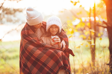 丰富多彩的秋天带杯子快乐母亲和小女孩在秋天温暖的日子里裹在一条美丽的家庭毯子里叶九月图片