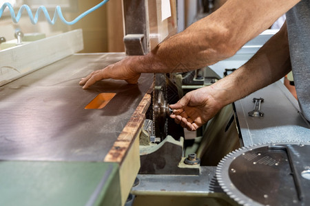 家具木匠在机器中安装新金属件以切断木柴的裁剪工作专业图片