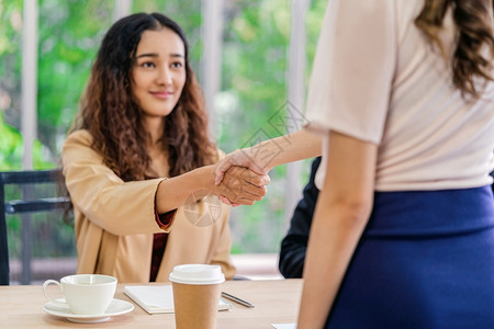 团体亚洲人在年轻妇女与两名在会议室有积极动的经理之间达成面谈协议后密切握手与经理企业雇用新会员概念经理握手并进行接触以及合伙图片