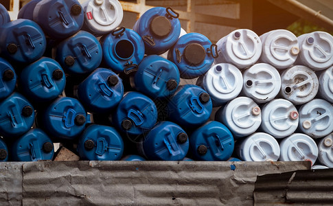 经过蓝色和白油桶塑料罐有毒废物仓库危险化学品桶工业废塑料空及QC出入证标签工业废塑料桶空罐和QC通行证标签柴油机生锈的图片