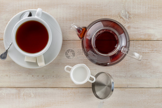 茶点热的新鲜木桌上玻璃茶壶热红和牛奶壶玻璃水热红茶杯和木桌上的牛奶壶顶视图图片