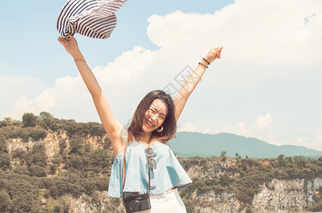 穿戴帽子和拉起手的漂亮美丽亚洲妇女在夏季旅行时身着高山和蓝天的模糊背景游客自由有魅力的图片