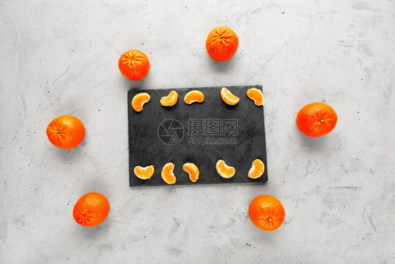 瘦身种子可口橘亮光和多汁的碎片躺在一块灰色的板上周围环绕着整个橙黄色橘子位于灰混凝土背景上复制空间Bright和多汁的曼达林切片图片