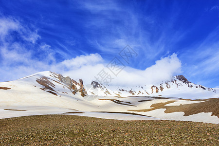 地面冰土耳其中部Erciyis山的雪顶被笼罩在白云中与阳光明媚的春天上蓝空相对土耳其中部Erciyas山的景象绿色图片