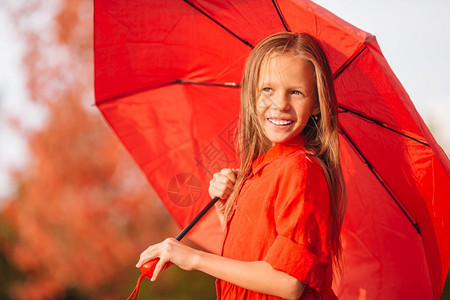 跳公园快乐可爱的小孩带着红雨伞在秋天走暖的一快乐孩子们女笑在红雨伞下玩图片