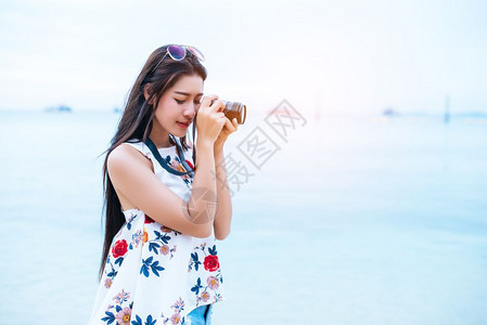 年轻的蓝色亚洲女人喜欢在海滩上用数码相机拍照单身和孤独的女人概念幸福和生活方式概念美丽和自然主题海洋背景技术女人节数字的图片