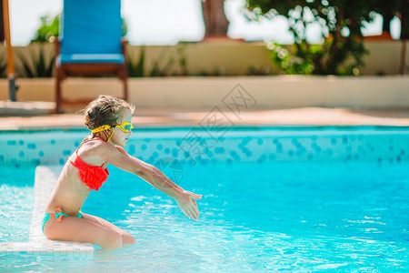 溅在户外游泳池里快乐可爱的小女孩有充气橡皮圈的女孩在豪华酒店的户外游泳池里玩得开心水色泳装图片
