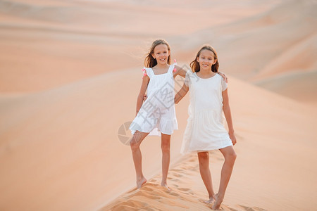 孩子滚动阿比在世界上最大沙漠中的丘上小美少女日落时在阿拉伯联合酋长国RubalKhali沙漠中的丘女孩图片