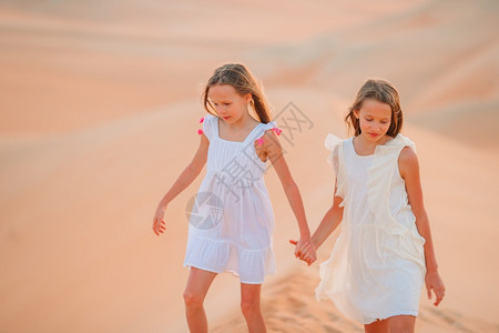 阳光女孩们世界最大沙漠中丘上的小美少女在阿拉伯联合酋长国鲁布哈利沙漠中女孩在丘上阿拉伯联合酋长国RubalKhali沙漠图片