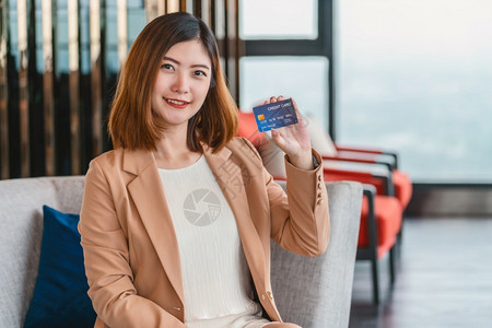 金融手指在现代大厅或工作空间咖啡杯技术资金钱包和在线支付概念信用卡模型网上购物时展示信用卡的亚洲肖光妇女提供信用卡在线购买的亚洲图片