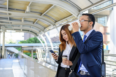 商业女人在镇上喝咖啡办公室外使用智能手机现代城市举起来抢走咖啡杯和智能电话与商业伙伴一起用咖啡谈生意伙伴的心话户外人们合伙图片