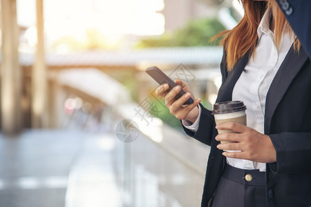 商业女人在镇上喝咖啡办公室外使用智能手机现代城市举起来抢走咖啡杯和智能电话与商业伙伴一起用咖啡谈生意伙伴的心话街道咖啡因讨论图片