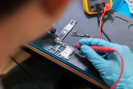 室内的定影电话修理概念一名年轻的电气技术员使用一个计量电子设备路流的仪表测量贮存图片
