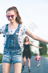 喜悦笑的年轻女孩在夏日共度愉快的滚溜乐趣旱冰鞋图片