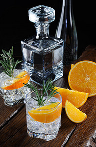 晚餐冷藏小酒杯鸡尾经典干金有汤力和橙色芝士木板上有一串迷迭香切片多汁的橙子图片