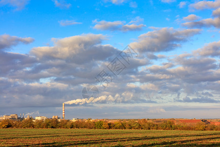 总计的明亮清晨秋天阳光照耀着农业田地的长阴影以工业综合体和蓝色天空中的浮云照亮地平线秋季风景明亮的晨光照了农业田地平线上的生产综图片