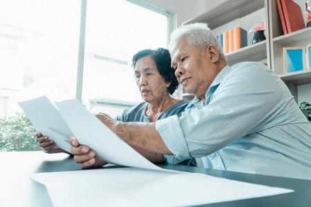 老年夫妇使用在家里办公桌上的计算器和书面文件计算费用收入和退休后储蓄计算退休后开支和收入及储蓄退休人员财务规划和投资概念退休人员图片