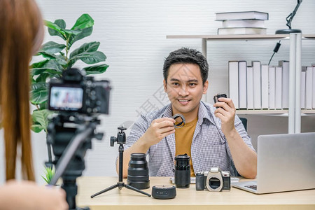 硬件男人营销亚洲Vlogger男子满意每个媒体的相机镜头摄像影机拍视频并用笔记本电脑直播通过社交媒体频道vlog和impactr图片