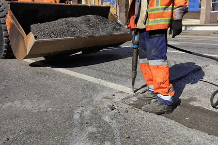 团队道路维修工人在施期间用一部手推机将旧沥青从公路上的旧沥青清除出来在道路建设过程中一名工人用台充气大锤清除了一块沥青男人行业图片