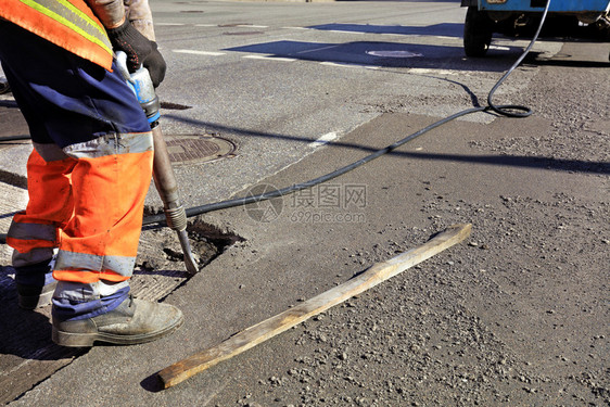 积极的黑色道路维修工人在施期间用一部手推机将旧沥青从公路上的旧沥青清除出来在道路建设过程中一名工人用台充气大锤清除了一块沥青干净图片