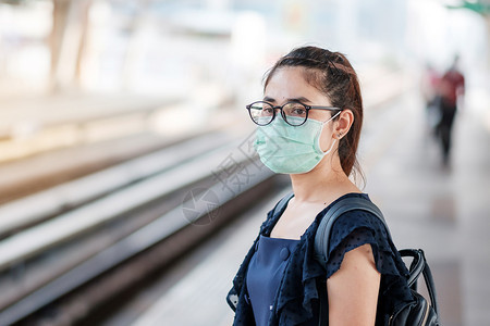 青年女性在公共火车站戴着口罩图片