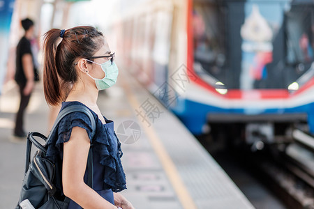 在公共火车站戴着口罩的青年女性图片