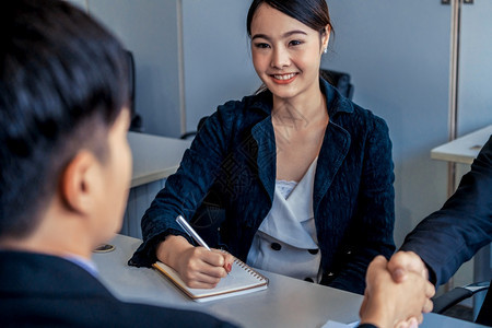 商务人士协议概念亚洲商人在办公室会议与另一位商人握手年轻的亚洲秘书女士坐在他旁边商务人士在办公室握手协议购买房间团队合作图片