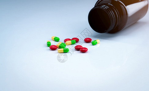 白色背景棕药瓶附近的绿和黄胶囊与红药片丸制工业止痛阿片类物衍生治疗癌症疼痛的药物包装红色曲马多图片