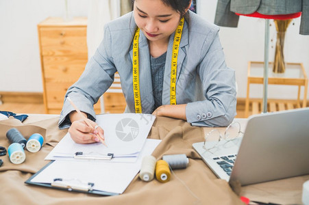 工具女孩在家庭办公室讲习班上工作的有吸引力亚洲时装设计师女时装设计师在家庭办公室工作时尚妇女创造新的布料设计汇编裁缝和纫材料图片