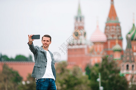 学生在圣巴西尔斯教堂和克里姆林宫肖像背景上有电话户外的青年男子莫斯科快乐城市青年男子欢乐在欧洲市商人的克里姆林宫肖像镇劳动图片