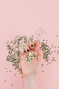 闪光极简主义新年或圣诞女双手的顶端观赏黑指甲覆盖金星的彩色面团复制了一千年空间粉红纸背景最起码风格的女博客社交媒体模板女士图片