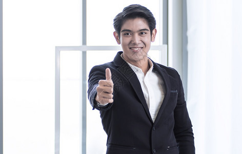 企业家一名身穿黑色西装的亚洲青年商人笑着成功并举起拇指英俊的幸福图片