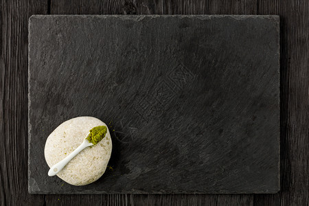 白色陶瓷勺中汤匙的红茶粉白石上用黑板制成的厨房切菜板黑在木色背景平地复制空间Matcha绿色茶粉在白石头和黑暗背景上的陶瓷勺中素图片