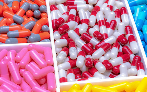 灰色的加粉彩在塑料托盘抗生素胶药丸中的红白橙光粉色蓝和黄胶囊药物工业治疗感染的首选药物抗菌剂图片